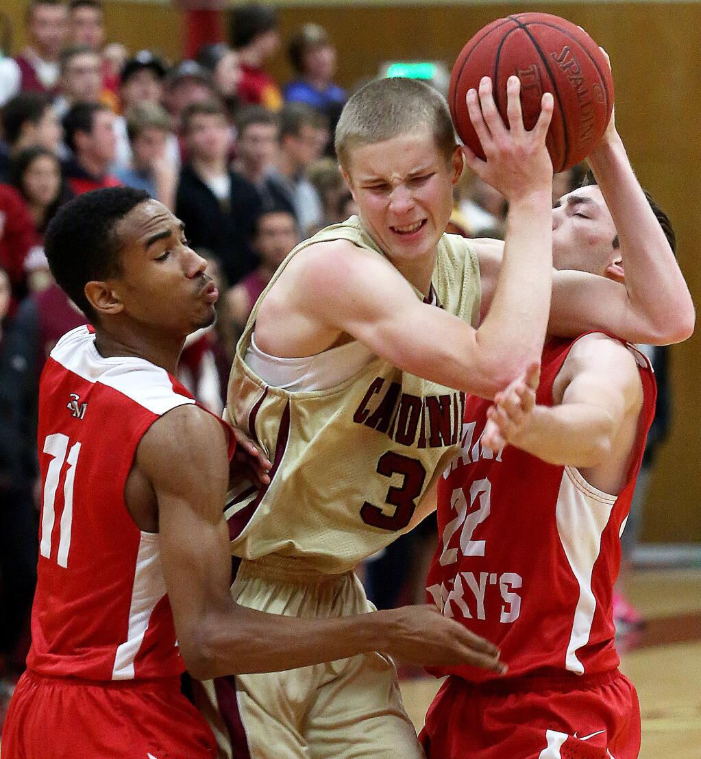 Cardinal Newman's Justin Botteri is double teamed by Saint Mary's Kevin Warren, left, and Jack Soldavini, right, during the championship game of the Rose City Tournament held at Cardinal Newman High School, Saturday, December 13, 2014. (Crista Jeremiason / The Press Democrat)