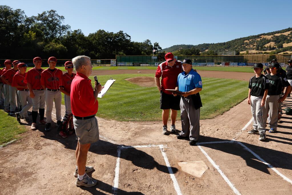 Longtime umpire Ron Nagy, center in blue, is presented with a commendation letter from the CEO of Little League Baseball by California Little League District 35 administrator Don Goodman, left, and District 35 umpire-in-chief Rod Lund before a game between the Petaluma National and Vacaville Central at Rincon Valley Little League Park in Santa Rosa, California on Wednesday, July 20, 2016. (Alvin Jornada / The Press Democrat)