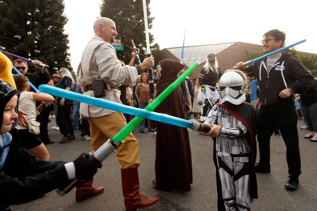 Juniper Perkinson, 5, right, dressed as the Star Wars character Captain Phasma duels her brother Sailor Perkinson, 8, left, while they and other Star Wars fans participate in a flash mob lightsaber duel and dance at the first Wednesday Night Market of the season in Santa Rosa, California on Wednesday, May 4, 2016. (Alvin Jornada / The Press Democrat)