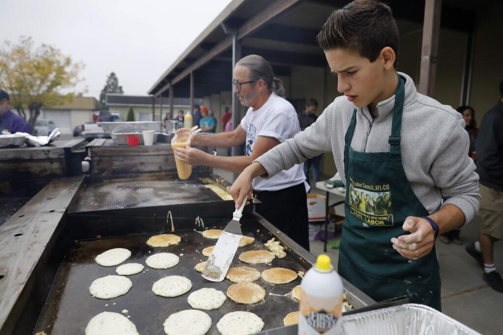 Eighth grader Jackson Boaz, right, and letter carrier Clay Cook cook pancakes and eggs for the buffet line during the North Bay Labor Council's annual Labor Day Pancake Breakfast at the Carpenters' Labor Center on Monday, September 3, 2018 in Santa Rosa, California . (BETH SCHLANKER/The Press Democrat)