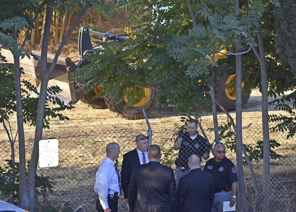 In this Aug. 1, 2018, photo, law enforcement officers stand by the scene behind the American Budget Inn on Kansas Avenue in Modesto, Calif. California police say a homeless woman sleeping in a cardboard box was struck and killed by heavy machinery operated by a road crew clearing a homeless camp, the Modesto Bee reported Wednesday, Aug. 29, 2018. State officials four months ago rejected a union grievance filed by Caltrans workers who object to clearing homeless encampments. The union argued unsuccessfully that workers lack safety equipment and training for the cleanups. (Deke Farrow/The Modesto Bee via AP)