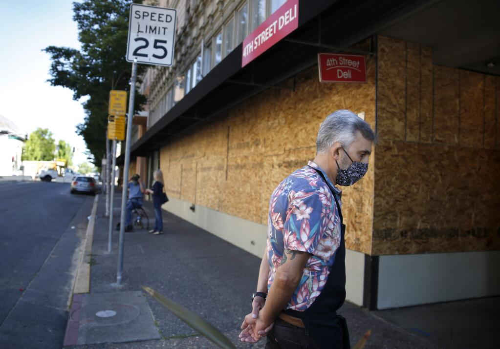 Neal Mogannam, co-owner of 4th Street Deli, walks in front of his shop which is open for business despite having boarded-up windows, in Santa Rosa, California on Thursday, June 4, 2020. (BETH SCHLANKER/The Press Democrat)