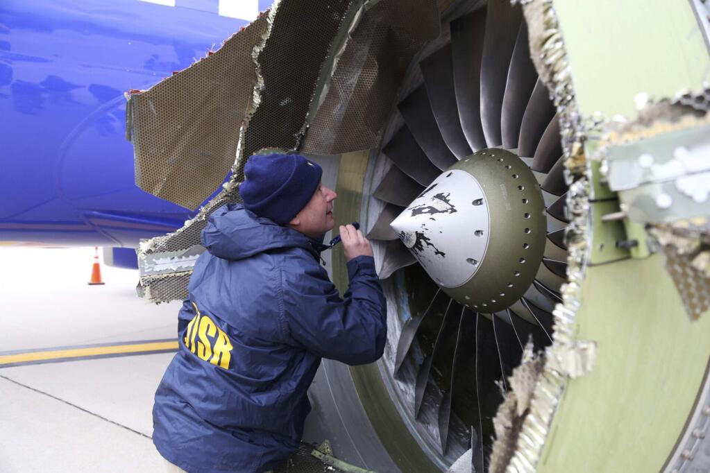 In this Tuesday, April 17, 2018 photo, a National Transportation Safety Board investigator examines damage to the engine of the Southwest Airlines plane that made an emergency landing at Philadelphia International Airport in Philadelphia. A preliminary examination of the blown jet engine of the Southwest Airlines plane that set off a terrifying chain of events and left a businesswoman hanging half outside a shattered window showed evidence of 'metal fatigue,' according to the National Transportation Safety Board. (NTSB via AP)