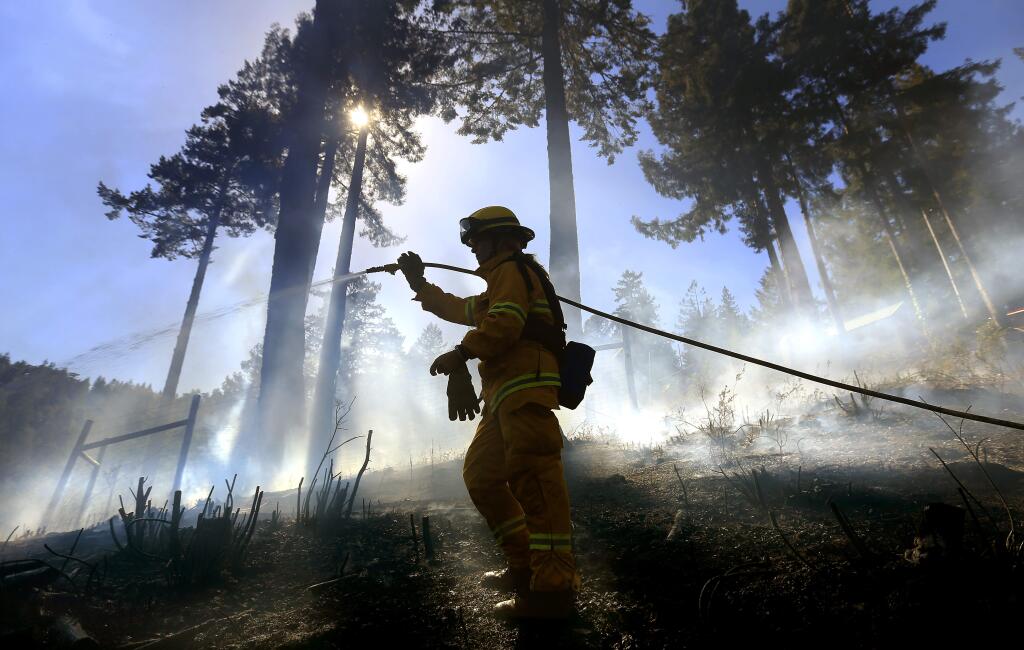 Monte Rio volunteer firefighter Gabriela Gibson, sprays down hot spots on a half acre fire in timber above Monte Rio, Friday April 10, 2015. A control burn slopped over containment lines and wind blew embers in to the timber, igniting drought stressed trees and brush. (Kent Porter / Press Democrat) 2015