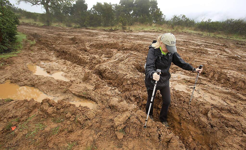 Anne Bettencourt of the Sierra Club gauges the depth of a tractor rut, Friday March 4, 2016 that was created by an event called BattleFrog, was held in February at Lake Sonoma on the Half-a- Canoe trail. (Kent Porter / Press Democrat) 2016
