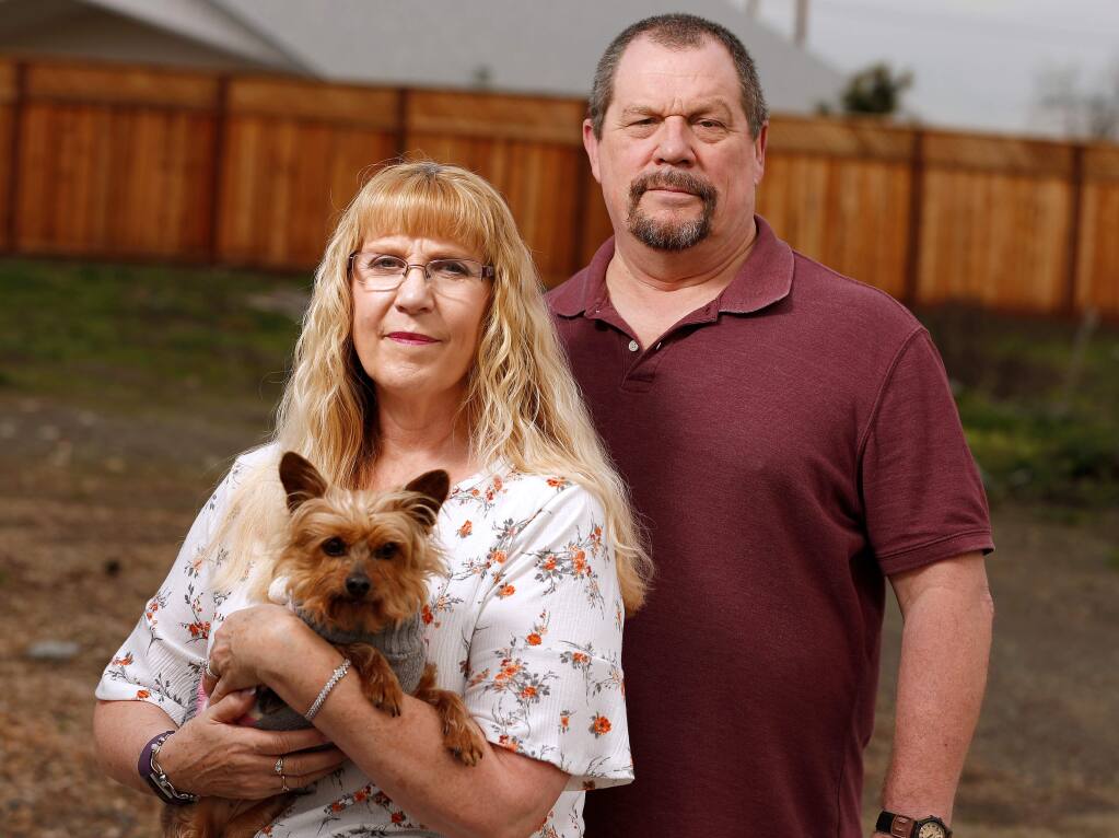 Jennifer and Wayne Harvell, with their dog Sophie, pose for a portrait where their home of 30 years stood on Mocha Lane before it burned down during the Tubbs Fire, in Santa Rosa, California, on Saturday, January 26, 2019. (Alvin Jornada / The Press Democrat)