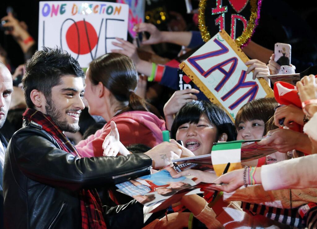 FILE - In this Sunday, Nov. 3, 2013 file photo, Zayn Malik of One Direction gives his autograph to Japanese fans during an event for their film 'One Direction: This Is Us', in Makuhari near Tokyo.Chart-topping boy band One Direction says Zayn Malik has left the group. The band confirmed his departure Wednesday, March 25, 2015 in a statement. (AP Photo/Koji Sasahara, File)