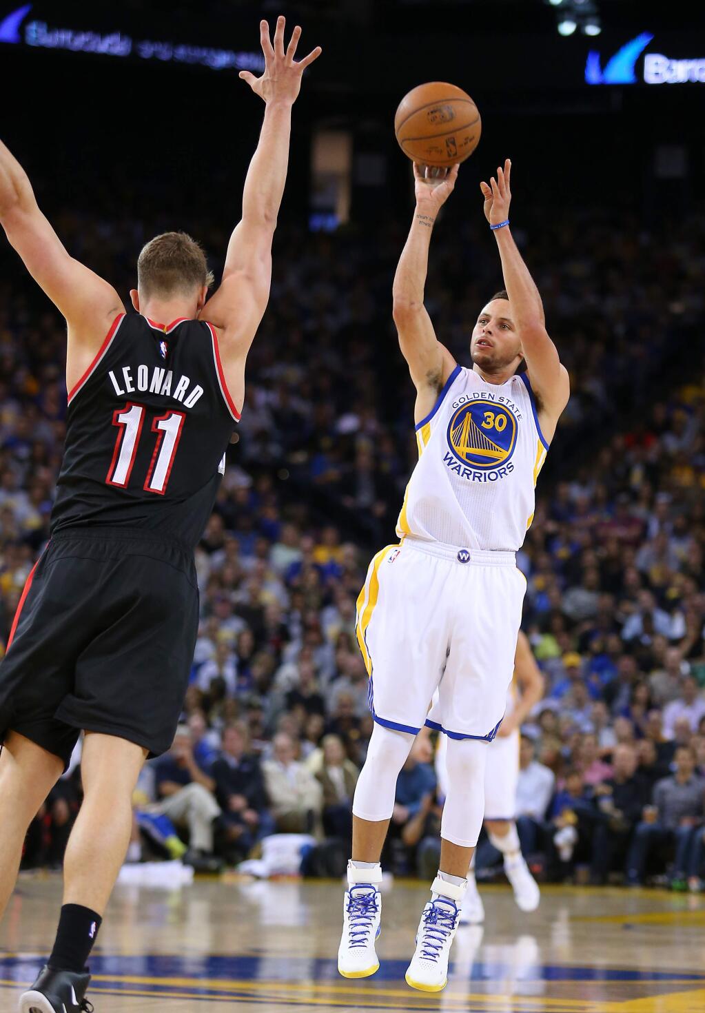 Golden State Warriors guard Stephen Curry hits a three-point shot over Portland Trailblazers center Meyers Leonard to break the single-season record for three-pointers, during their game in Oakland on Thursday, April 9, 2015. (Christopher Chung/ The Press Democrat)