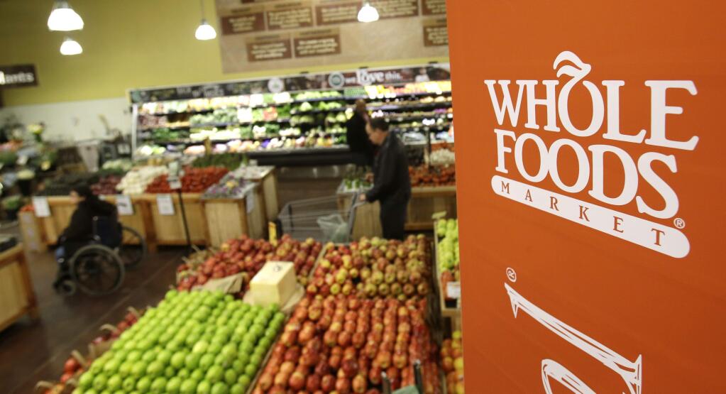 This March 27, 2014 photo shows shoppers in the produce section at the the Whole Foods Market in Woodmere Village, Ohio. Whole Foods reports quarterly financial results on Wednesday, May 6, 2015. (AP Photo/Tony Dejak)