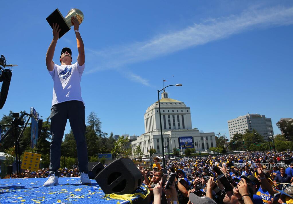 Warriors guard Klay Thompson holds up the Larry O'Brien Championship Trophy in front of fans at the end of the Warriors Championship Parade and Rally in Oakland on Thursday, June 15, 2017. (CHRISTOPHER CHUNG/ PD)