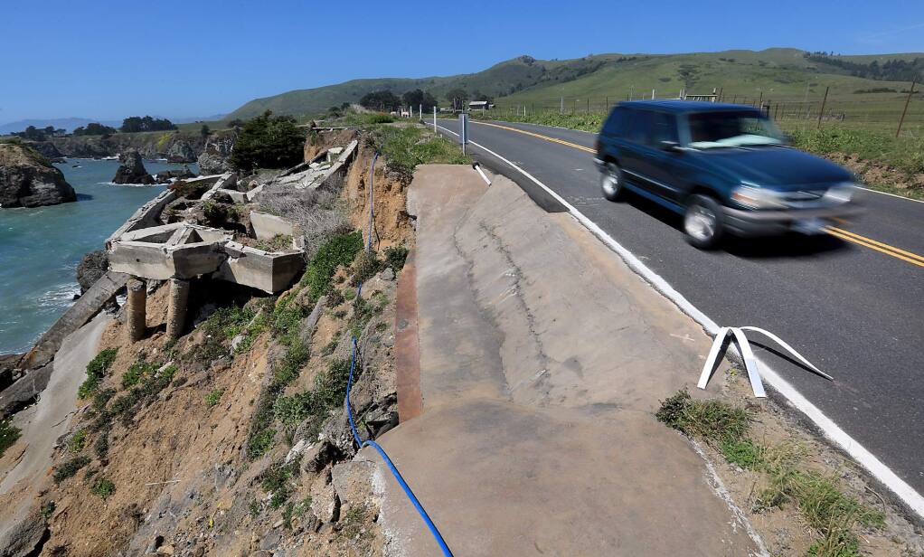 With just a foot or two of space, cars zoom past a section of Highway 1 roadway that has crumbled and shored up to prevent further erosion at Gleason Beach north of Bodega Bay, Tuesday, May 1, 2018 Foundations of homes still exist on the hillside. (Kent Porter / The Press Democrat) 2018