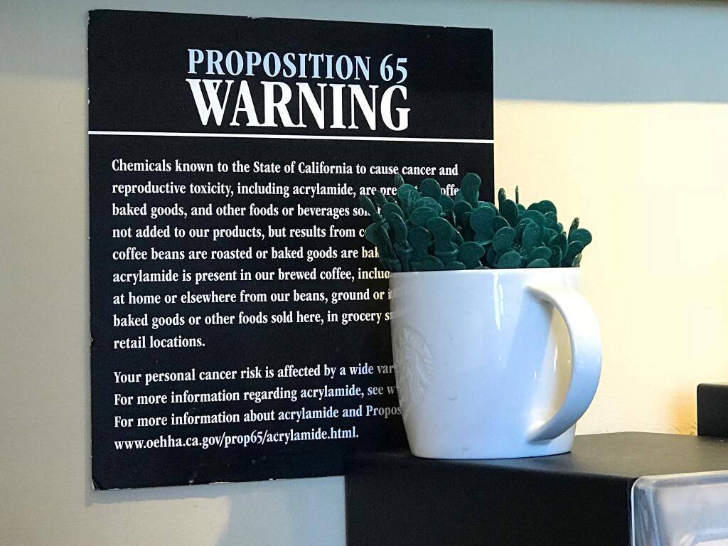 FILE - In this March 30, 2018, file photo, a posted Proposition 65 warning sign is seen on display at a coffee shop in Burbank, Calif. State health officials proposed a regulation change Friday, June 15, 2018, that would declare coffee doesn't present a significant cancer risk, countering a recent California state court ruling that had shaken up some coffee drinkers. (AP Photo/Damian Dovarganes, File)