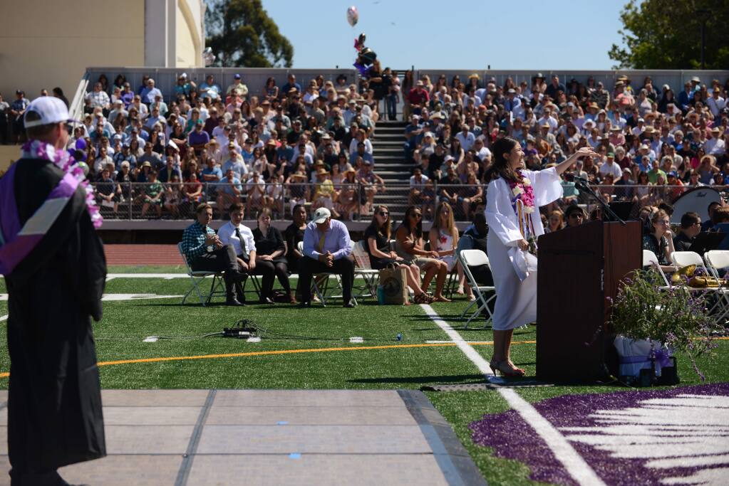 Petaluma High School Principal David Stirrat, left, watches Lulabel Seitz, right, gesturing for crowd support which she loudly received after her microphone was shut off by school officials during her valedictorian speech at the Petaluma High School Graduation ceremony held Saturday in Petaluma, California. June 2, 2018.(Photo: Erik Castro/for The Press Democrat)