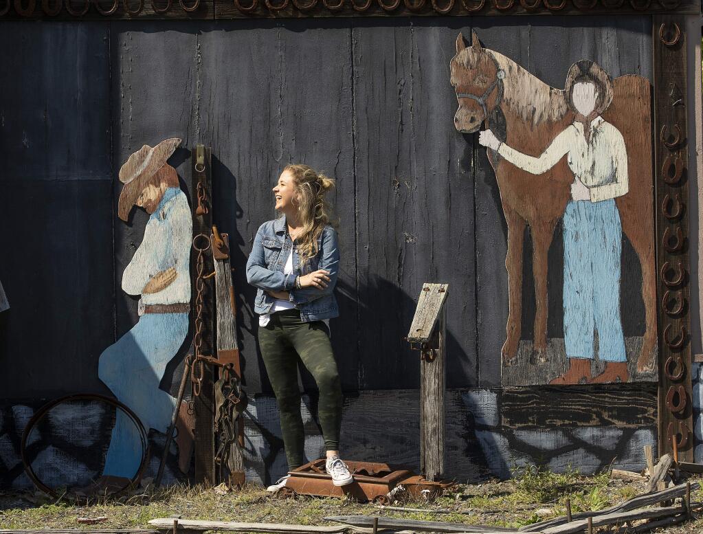 Shawna DeGrange, owner of the Cloverleaf Ranch, stands with cutouts painted by her uncle on one of the few buildings left after the Tubbs Fire in 2017. (Photo by John Burgess/The Press Democrat)