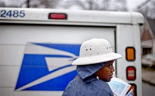 In this Feb. 7, 2014 file photo, U.S. Postal Service letter carrier Jamesa Euler, delivers mail in the rain in the Cabbagetown neighborhood, in Atlanta. (DAVID GOLDMAN/ASSOCIATED PRESS)