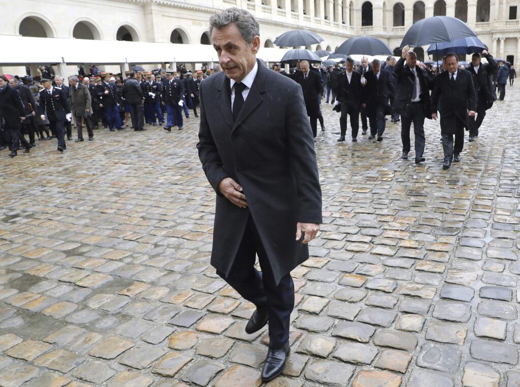 In this photo taken Wednesday March 28, 2018, former French President Nicolas Sarkozy leaves after a ceremony for late Lt. Col. Arnaud Beltrame at the Hotel des Invalides in Paris. A judicial official says Thursday March 29, 2018 that judges issued an order for Sarkozy to stand trial on accusations that he tried to illegally get information from a judge about an investigation targeting him. (Ludovic Marin, Pool via AP)