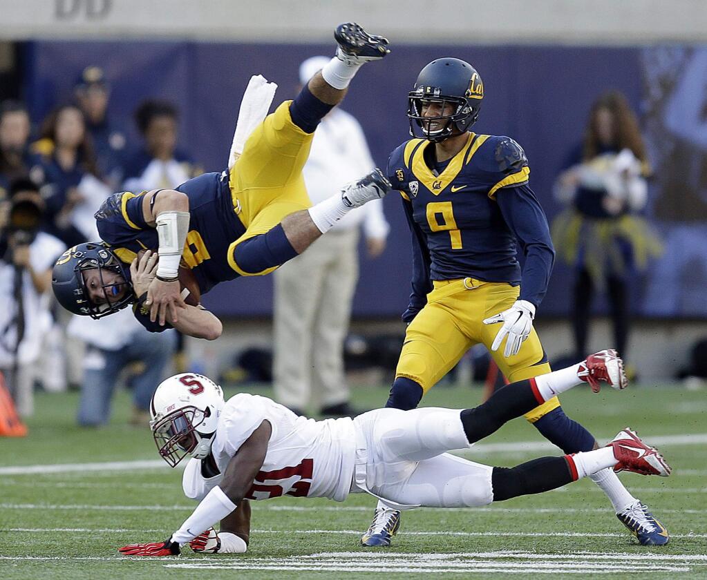 Stanford's Ronnie Harris (21) upends California quarterback Luke Rubenzer (8) during the second half of an NCAA college football game Saturday, Nov. 22, 2014, in Berkeley, Calif. At right is California's Trevor Davis (9). (AP Photo/Ben Margot)