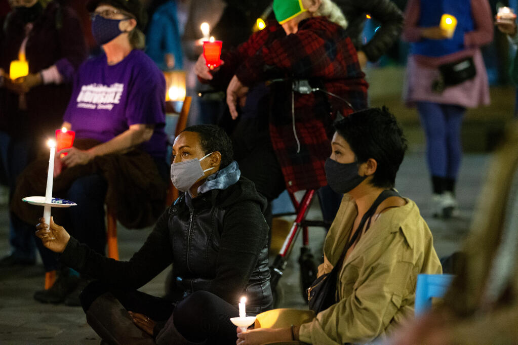 Faven Zewdi, at lower left, and other attendees listen to speakers during a candlelight vigil for peace and democracy organized by the Clergy Caucus of the North Bay Organizing Project and the Unitarian Universalist congregation at Old Courthouse Square in Santa Rosa on Thursday, Nov. 5, 2020. (Alvin A.H. Jornada / The Press Democrat)