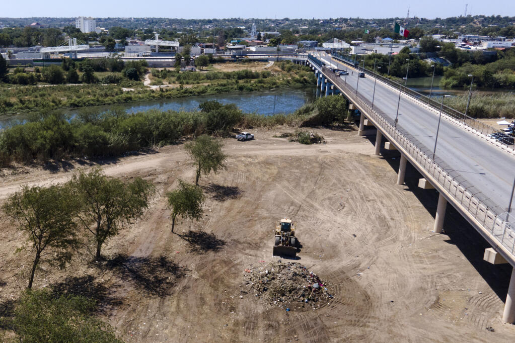 A bulldozer is seen next to a mound of debris while crews clear an area where migrants, many from Haiti, were encamped along the Del Rio International Bridge, Friday, Sept. 24, 2021, in Del Rio, Texas. (AP Photo/Julio Cortez)