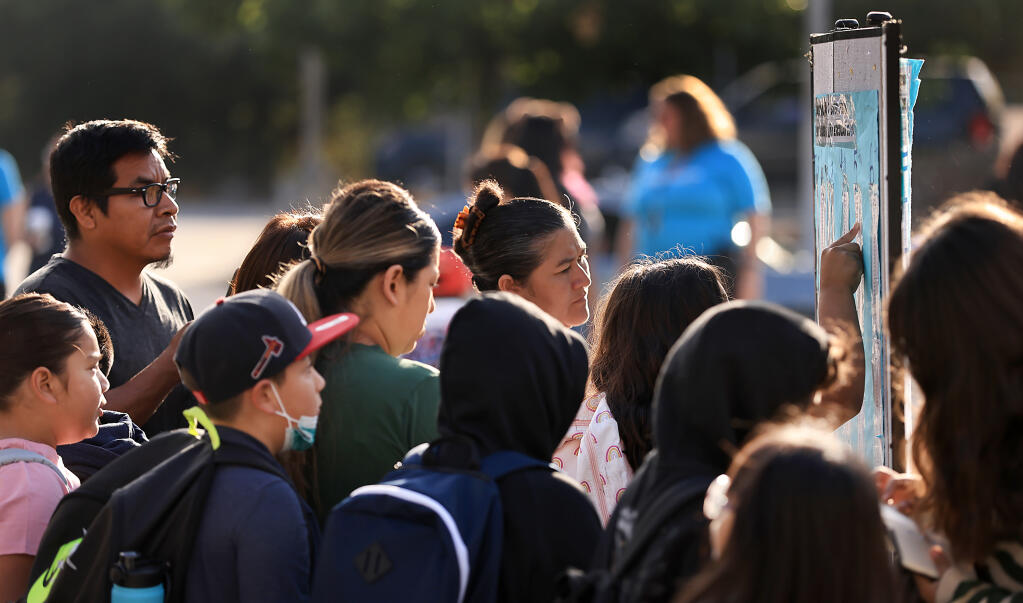 Parents with their Roseland Creek Elementary School students check their room assignments during the first day of school in Santa Rosa, Tuesday, Aug, 15, 2023. (Kent Porter / The Press Democrat)