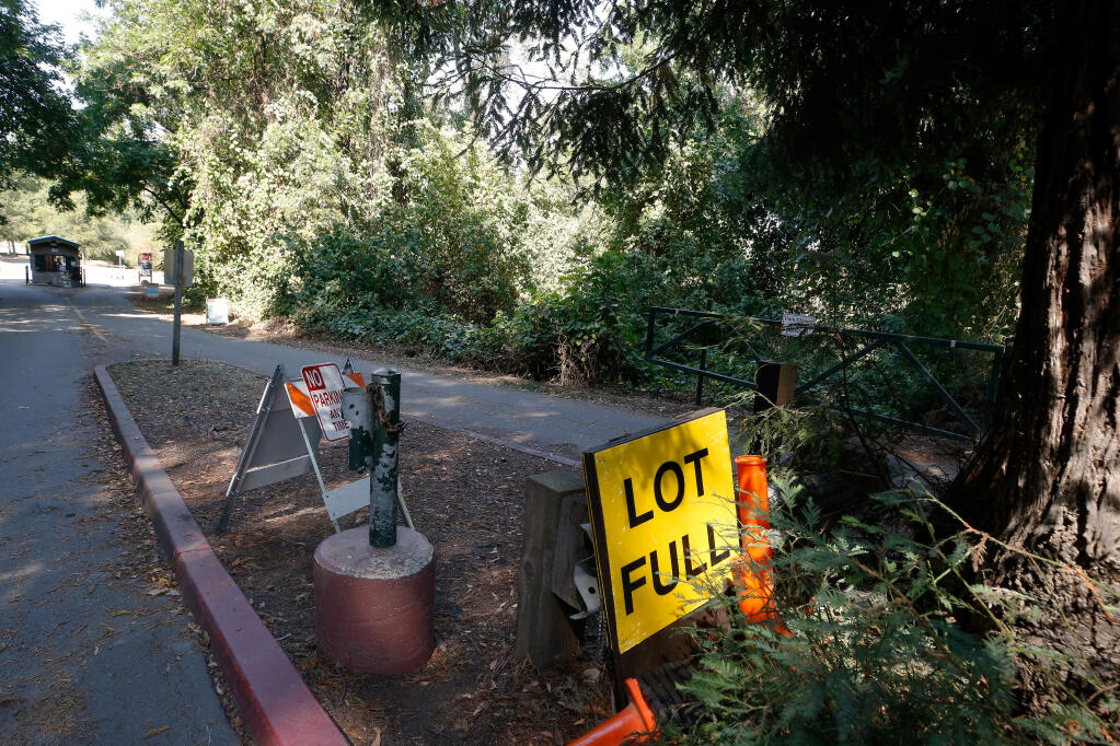The full parking lot sign and some traffic cones are hidden behind a redwood tree near at the front gates of Steelhead Beach Regional Park in Forestville, California, on Thursday, Sept. 3, 2020. Sonoma County Regional Parks along the Russian River have reopened after the Walbridge fire. (Alvin A.H. Jornada / The Press Democrat)