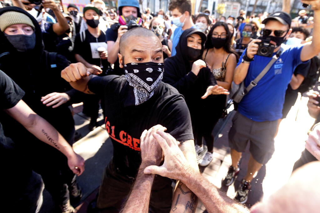 A counter-protester, who declined to give his name, prepares to hit a conservative free speech rally organizer in San Francisco on Saturday, Oct. 17, 2020. About a dozen pro-Trump demonstrators were met by several hundred counter-protesters as they tried to rally. (AP Photo/Noah Berger)