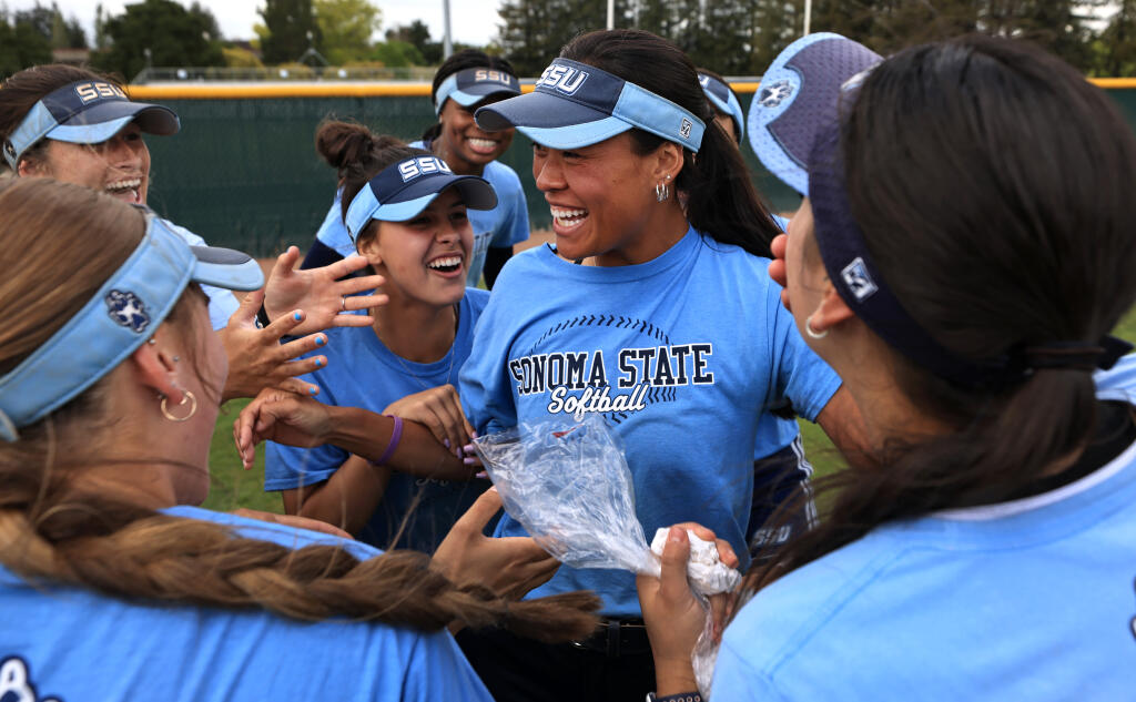 Sonoma State University’s Anna Zoia-Buescher, middle, is mobbed by teammates after Zoia-Buescher was chosen as  the California Collegiate Athletic Association’s player of the year, Tuesday, May 2, 2023, during a team practice on the SSU campus in Rohnert Park. (Kent Porter / The Press Democrat) 2023