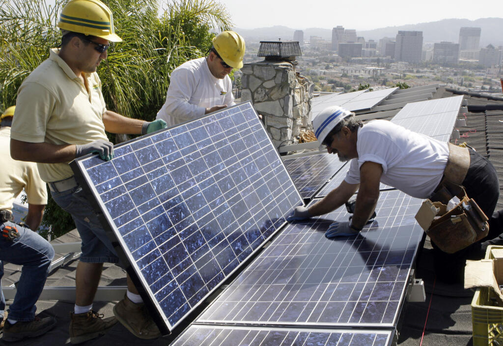 California Green Design assembles solar electrical panels on the roof of a home in Glendale, California, in 2010. (AP Photo/Reed Saxon, file)