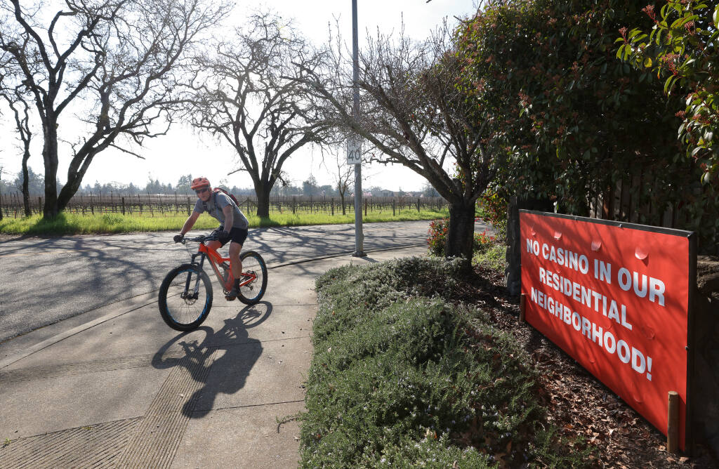 A cyclist rides past a large sign Monday, Feb. 14, 2022, on the corner of Mathilde Drive and Shiloh Road opposing a proposed casino in Windsor. The entertainment center is slated for the southeast corner of Shiloh Road and Old Redwood Highway. (Christopher Chung/The Press Democrat)