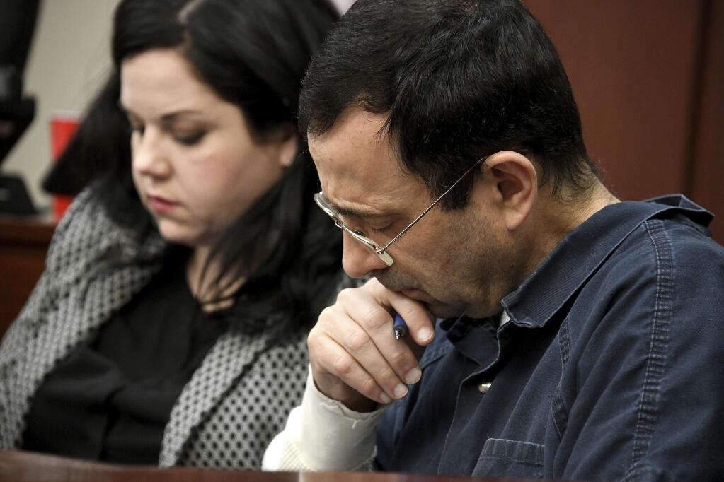 A victim makes her 'impact statement' to Larry Nassar during a sentencing hearing as he puts his head down in front of Judge Rosemarie Aquilina in district court on Tuesday, Jan. 16, 2018, in Lansing, Mich. Nassar has pleaded guilty to molesting females with his hands at his Michigan State University office, his home and a Lansing-area gymnastics club, often while their parents were in the room. (Dale G. Young/Detroit News via AP)