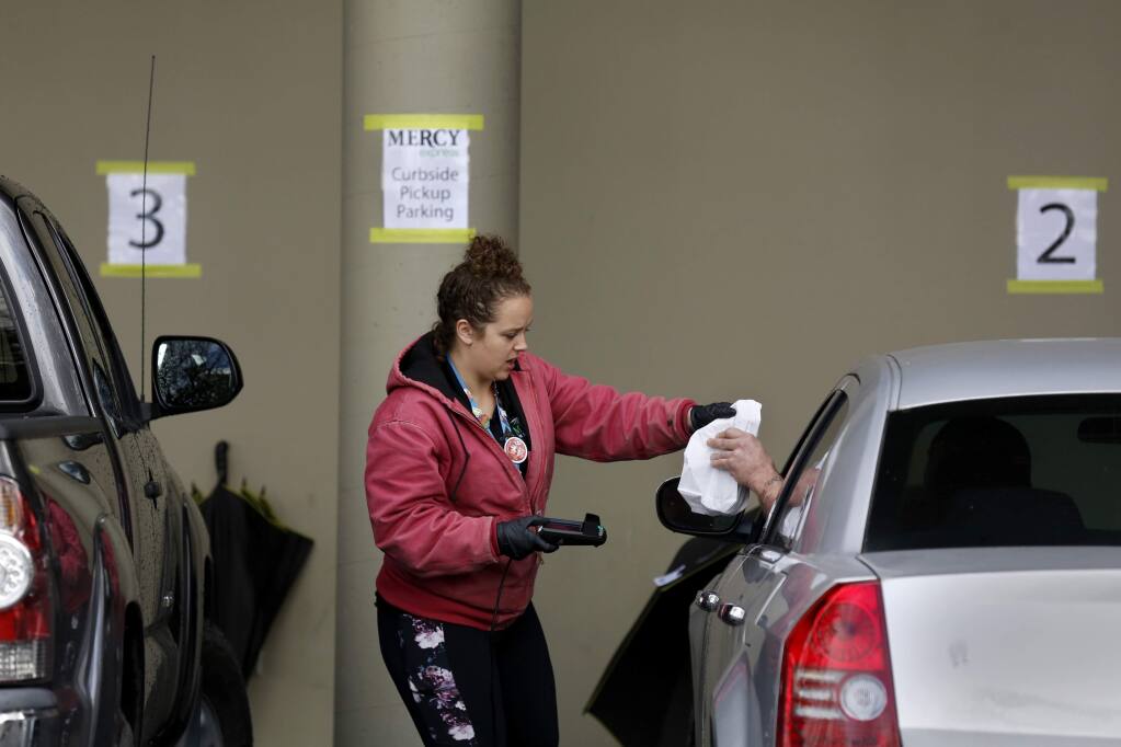 Employee Cari Garcia checks out a customer as part of the new curbside pickup at Mercy Wellness dispensary in Cotati on Tuesday, March 24, 2020. (BETH SCHLANKER/ The Press Democrat)