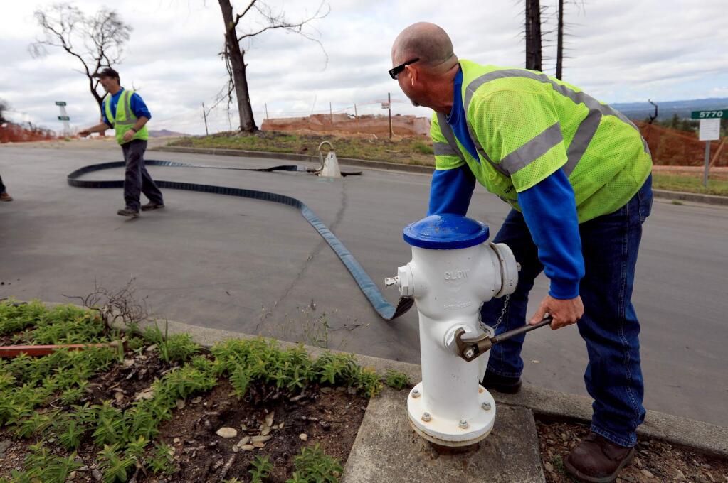 Anthony Drolet, right, and Tom Lynn, utility systems operators with the City of Santa Rosa, prepare to flush a water line in the Foutaingrove area of Santa Rosa, Wednesday, May 16, 2018, The water was emptied in to the city sewer system. (Kent Porter / The Press Democrat) 2018