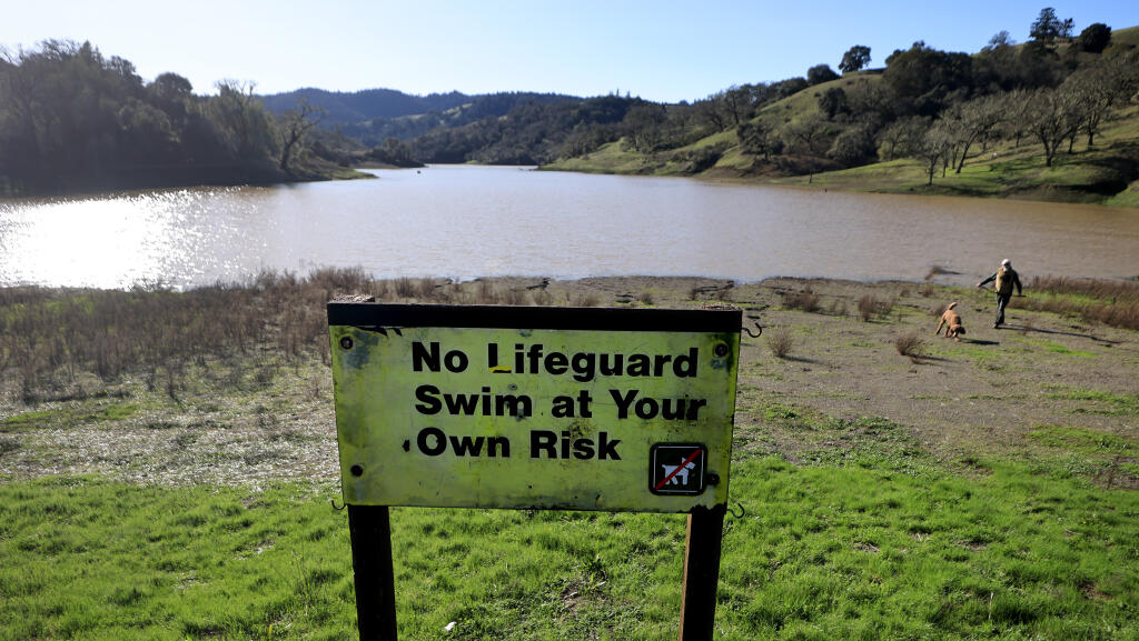 Rocky Bass, of Cloverdale, takes his dog Snoki for a walk at the Yorty Creek day use area at Lake Sonoma, Tuesday, Jan. 17, 2023, as the lake level continues to rise after nearly a month of rain. (Kent Porter/The Press Democrat)