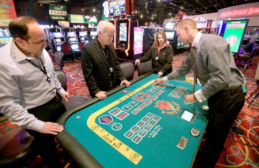 From left Tim De Lugo, Director of Casino Operations, David Fendrick, CEO of River Rock and Anne Pagel, Director of Player Development demonstrate how a game of Turn and Burn craps is played, Tuesday July 21, 2015 at River Rock Casino in Geyserville. At right is Pit Supervisor Joshua Mitchell of Santa Rosa. (Kent Porter / Press Democrat) 2015