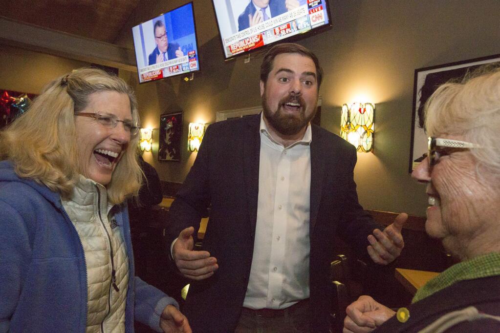 At Murphy's Irish Pub, Logan Harvey talks with supporters after initial early results place him in third place, thus assuring him a win, in the City Council election. (Photo by Robbi Pengelly/Index-Tribune)