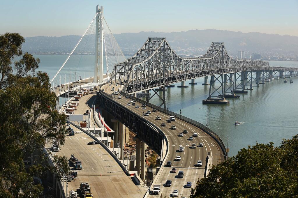The new extension of the Oakland-San Francisco Bay Bridge, left, gets ready to open before the old extension, right, is closed forever on Tuesday, Aug. 27, 2013. (Conner Jay/The Press Democrat)