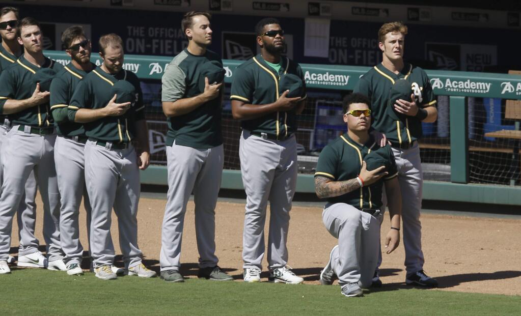Oakland Athletics catcher Bruce Maxwell takes a knee next to teammate Mark Canha, right, during the national anthem before a baseball game against the Texas Rangers in Arlington, Texas, Sunday, Oct. 1, 2017. (AP Photo/LM Otero)