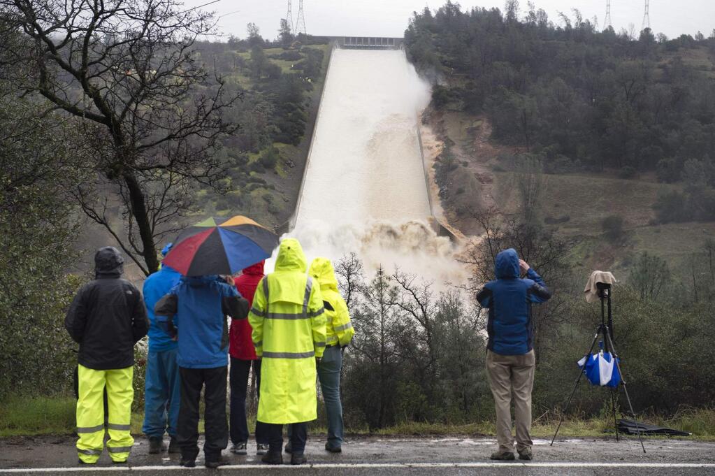 Department of Water Resources workers and members of the media watch as up to 20,000 cubic feet per second of water is released over the damaged spillway on Wednesday, Feb. 8, 2017 in Oroville, Calif. The Department of Water Resources said the erosion at Lake Oroville does not pose a threat to the earthen dam or public safety, and the reservoir has plenty of capacity to handle the continuing rain. (Randy Pench/The Sacramento Bee via AP)
