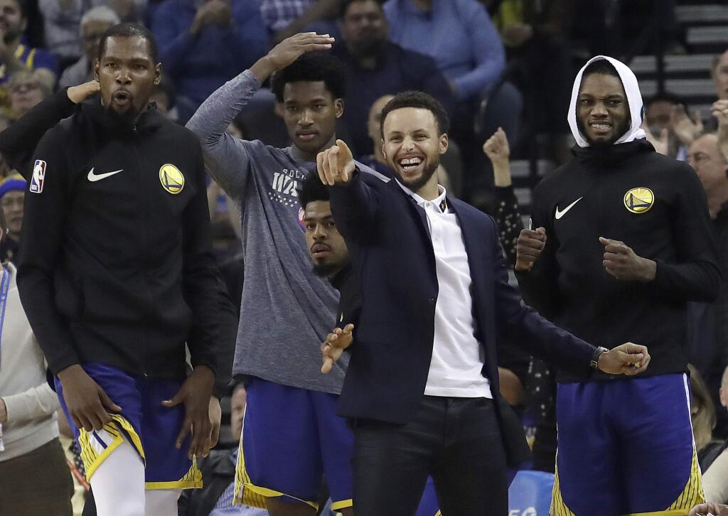 Injured Golden State Warriors guard Stephen Curry, foreground, celebrates with Kevin Durant, from left, Damian Jones, Quinn Cook and Alfonzo McKinnie during the second half against the Atlanta Hawks in Oakland, Tuesday, Nov. 13, 2018. (AP Photo/Jeff Chiu)