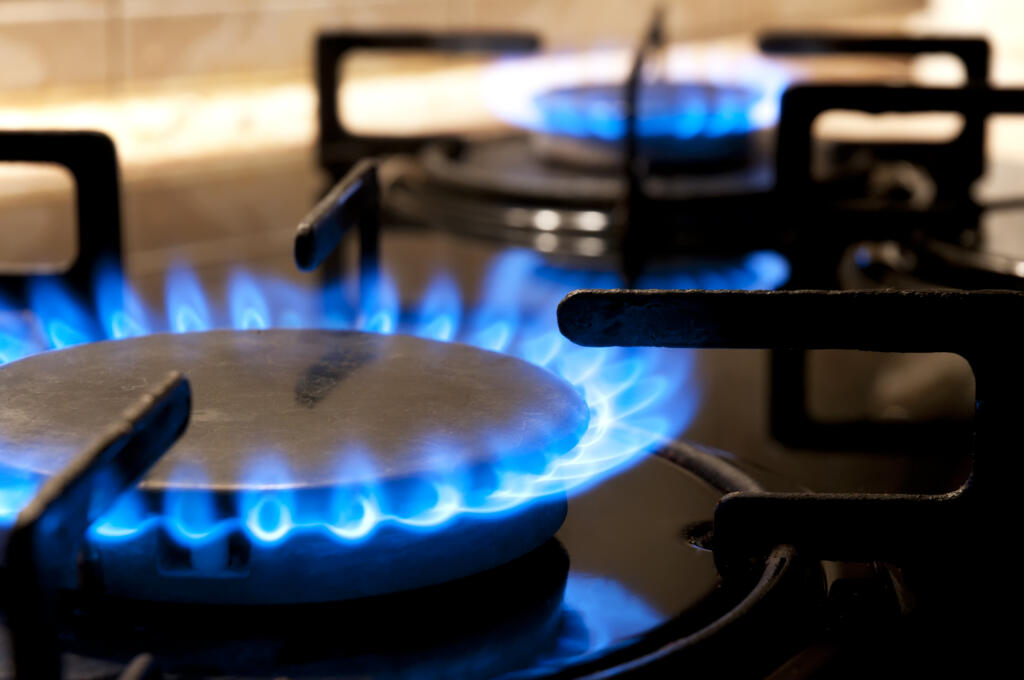 Close-up of a black gas stove top with two burning flames.