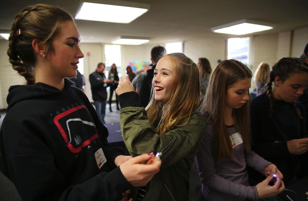 Presentation School seventh-grader Riley Wilde, center, proudly shows the flashlight she put together to schoolmate Kenzie Blair, left, during the STEAM showcase hosted by the Sonoma County Office of Education in Santa Rosa on Friday, March 3, 2017. (Christopher Chung/ The Press Democrat)