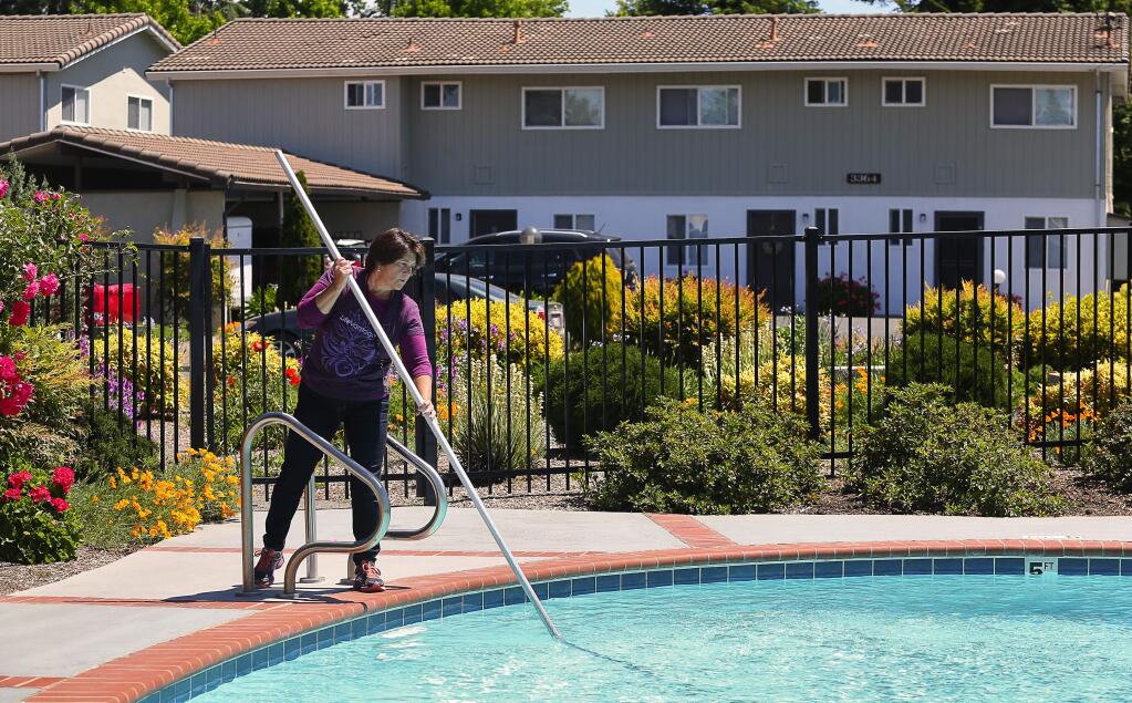 Brookside East Apartments manager Laura Rammer cleans the pool at the apartment complex in Santa Rosa on Monday, May 15, 2017. (Christopher Chung/ The Press Democrat)