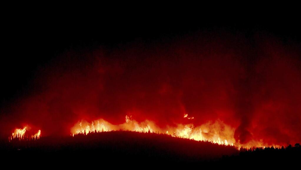 A wall of flames hundreds of feet high burn on a ridge above Rowan Road south of Lolo, Montana, early Thursday, Aug. 17, 2017. About 400 homes south and west of Lolo were evacuated because of the proximity of the Lolo Peak fire. (Kurt Wilson /The Missoulian via AP)