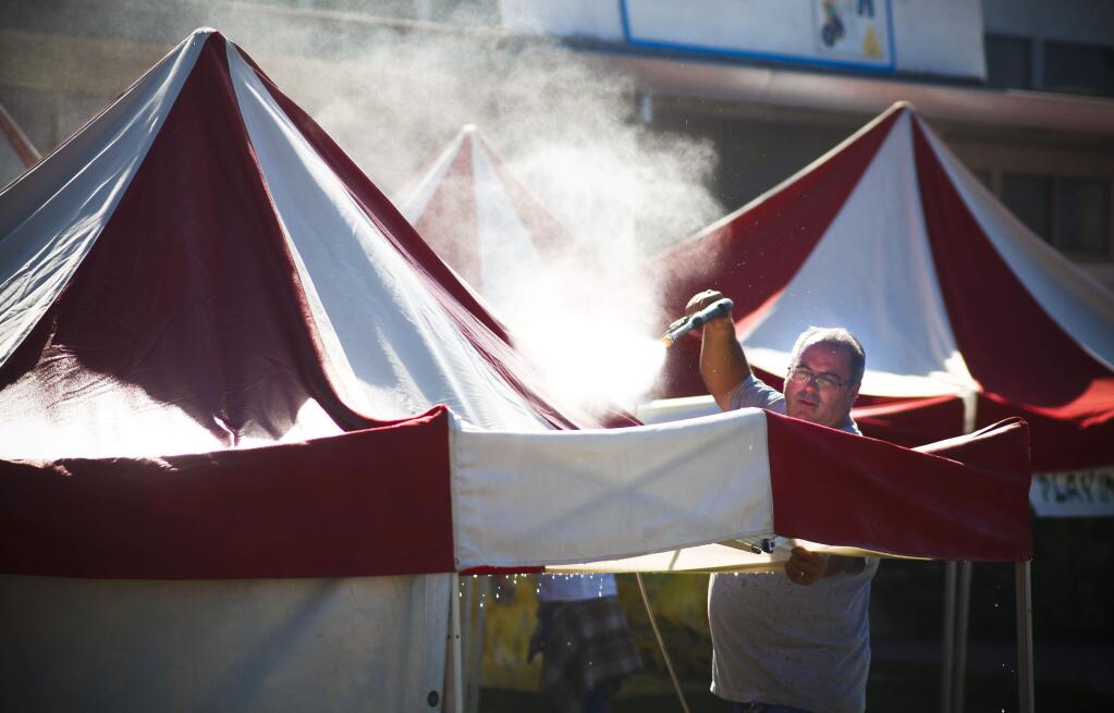 Petaluma, CA, USA. Tuesday, June 20, 2017._Manuel Lawrence, a manager with Great American Entertainment hoses down the pop-up tents where the 'Agventure' for kids area is being set-up for the annual Sonoma-Marin Fair. The Fair runs from June 21st-25th. (CRISSY PASCUAL/ARGUS-COURIER STAFF)