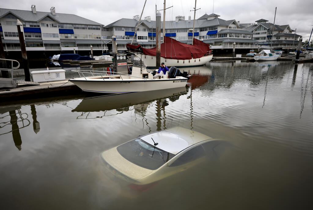 Boaters had to dodge a white sedan that was abandoned down the launch ramp at the Sheraton Hotel, Sunday, June 5, 2022 in the Petaluma River. The vehicle was eventually towed out of the water.  (Kent Porter / The Press Democrat) 2022