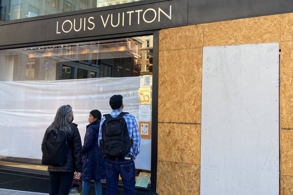 Union Square visitors look at damage to the Louis Vuitton store on Nov. 21, 2021, after looters ransacked businesses in San Francisco. Groups of thieves, some carrying crowbars and hammers, smashed glass cases and window displays, ransacking high-end stores throughout the San Francisco Bay Area, stealing jewelry, sunglasses, suitcases and other merchandise before fleeing in waiting cars. (Danielle Echeverria/San Francisco Chronicle via AP, File)