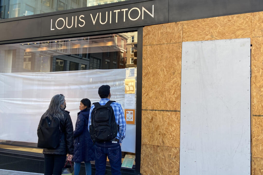 FILE - Union Square visitors look at damage to the Louis Vuitton store on Nov. 21, 2021, after looters ransacked businesses in San Francisco. Groups of thieves, some carrying crowbars and hammers, smashed glass cases and window displays, ransacking high-end stores throughout the San Francisco Bay Area, stealing jewelry, sunglasses, suitcases and other merchandise before fleeing in waiting cars during a weekend of brazen organized theft that shocked holiday shoppers and prompted concerns about the busy retail season. (Danielle Echeverria/San Francisco Chronicle via AP, File)