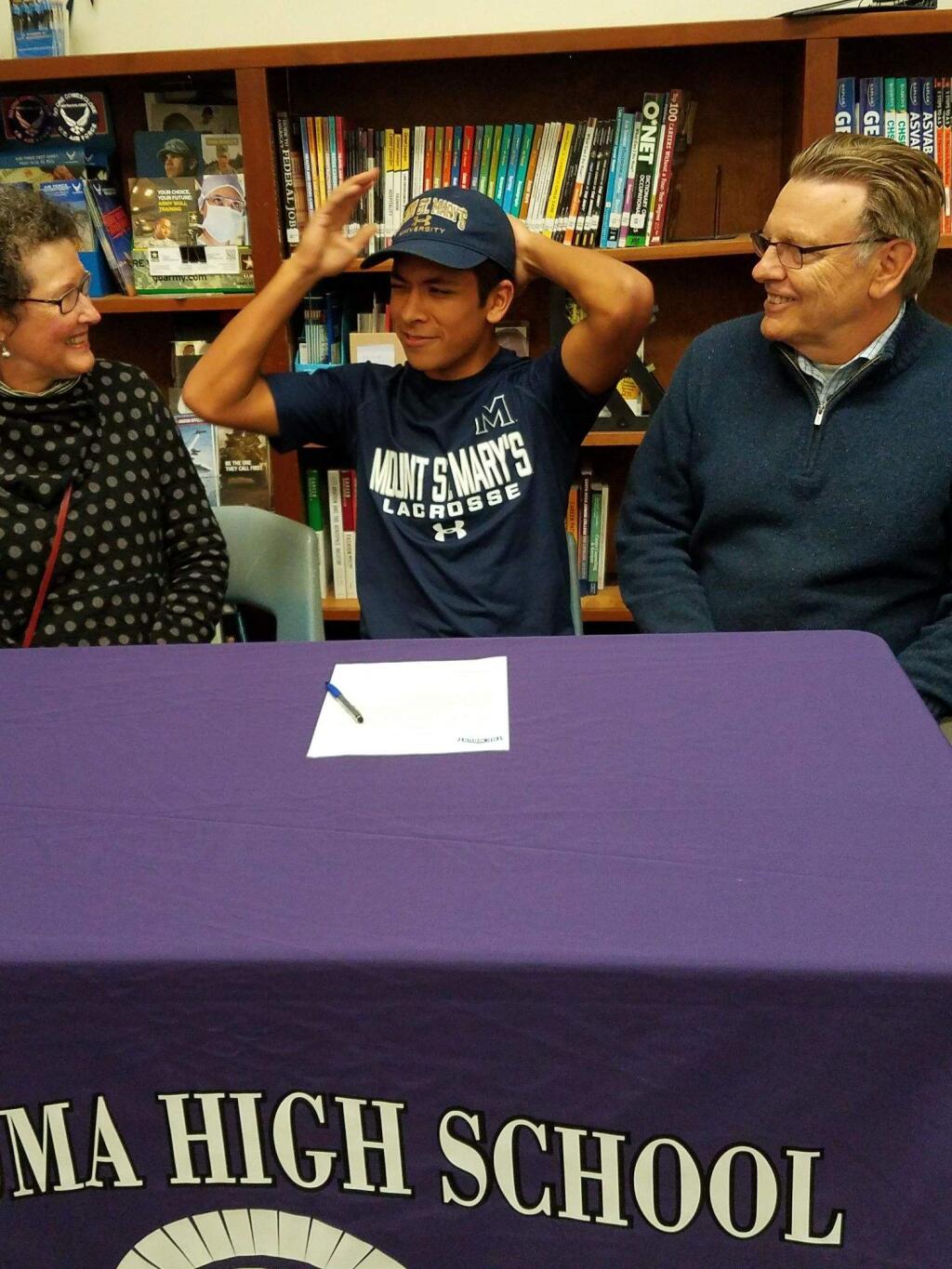 JOHN JACKSON/ARGUS-COURIER STAFFPetaluma High School senior Isaiah Blomgren tries on a Mount St. Mary's cap while proud mother, Peggy, and father, Carl, look on after the athlete signed to play lacrosse for the Maryland university.