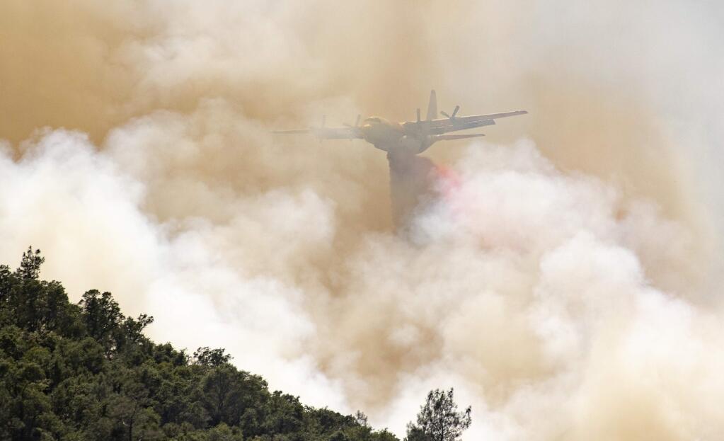 A firefighting aircraft drops fire retardant on a hillside in an attempt to box in flames from a wildfire locally called the Sand fire in Rumsey, Calif., Sunday, June 9, 2019. (AP Photo/Josh Edelson)