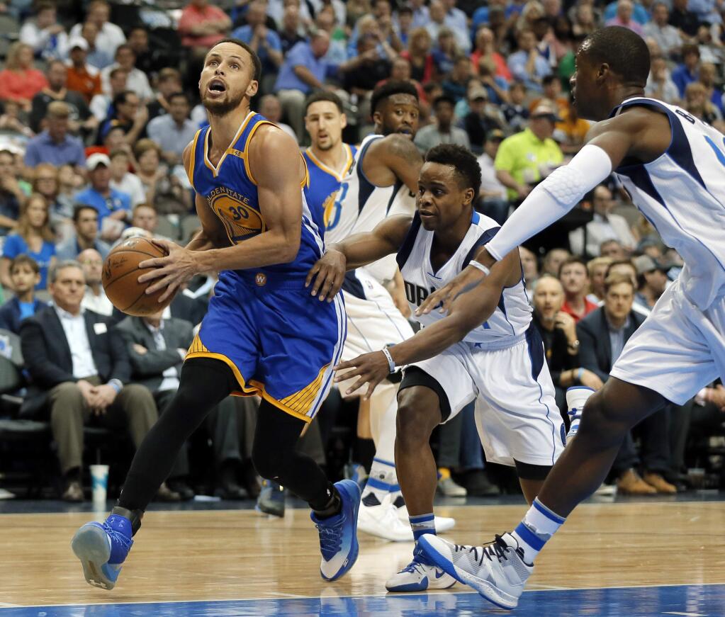 The Warriors' Stephen Curry, left, drives to the basket for a shot, drawing double coverage from the Dallas Mavericks' Yogi Ferrell, center, and Harrison Barnes, right, in the first half of Tuesday's game in Dallas. (AP Photo/Tony Gutierrez)